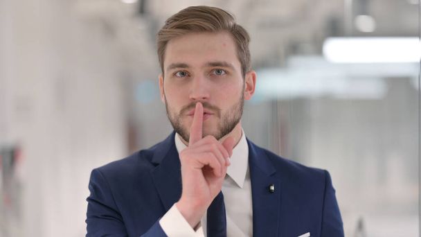 Νεαρός επιχειρηματίας δείχνει ήσυχο σημάδι, Δάχτυλο στα χείλη  - Φωτογραφία, εικόνα
