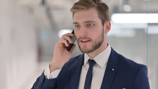 Агресивний молодий бізнесмен розмовляє по телефону
 - Фото, зображення