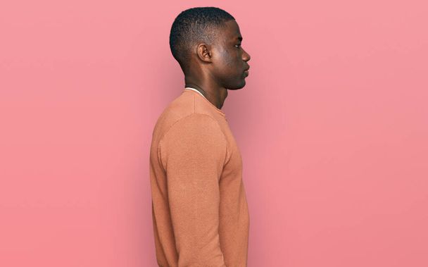 Joven afroamericano hombre usando ropa casual mirando a un lado, relajarse pose perfil con cara natural con sonrisa confiada.  - Foto, Imagen