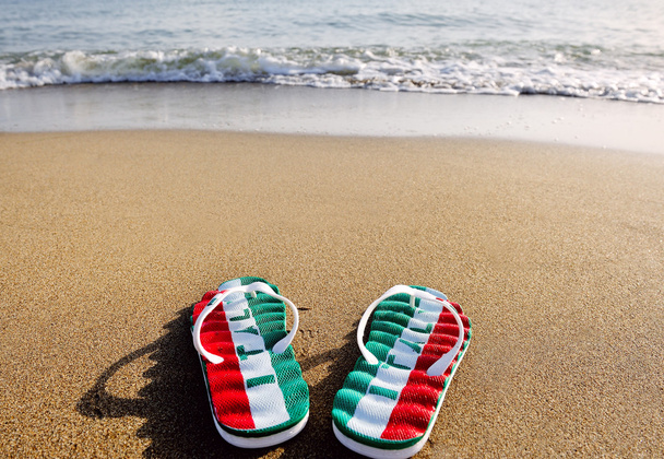 chanclas con la palabra Italia en arena de playa - vacaciones y concepto de relajación
 - Foto, Imagen