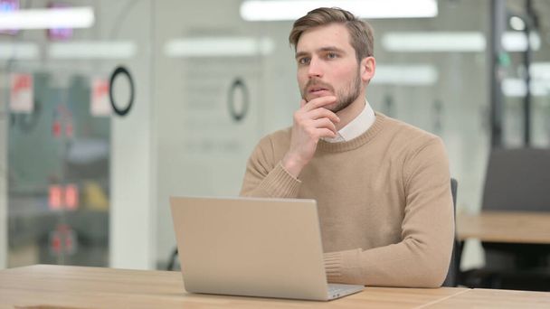 Young Man with Laptop, Thinking in Office  - Foto, Bild