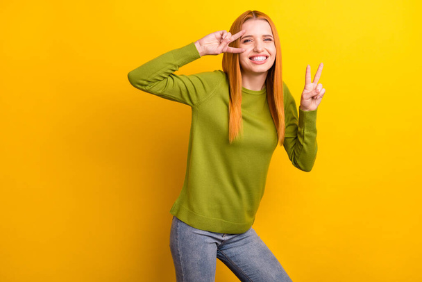 Photo of cool red hair young lady show v-sign wear green pullover isolated on yellow color background - Valokuva, kuva