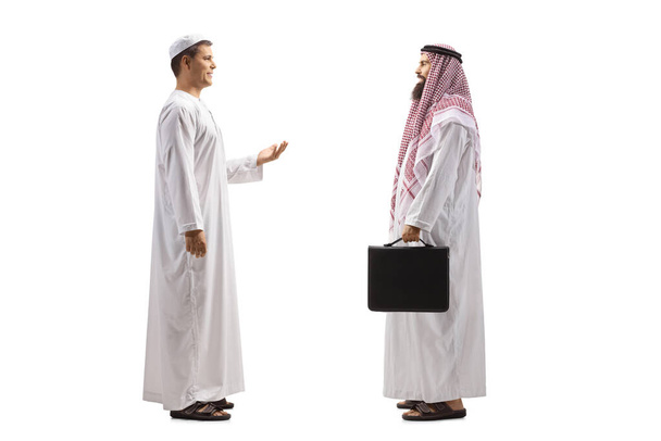 Full length profile shot of an arab man talking to a saudi arab businessman isolated on white background - 写真・画像