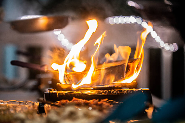 Sartén de cobre envuelta en llamas en el quemador de cocina en el buffet de resort al aire libre - Foto, Imagen