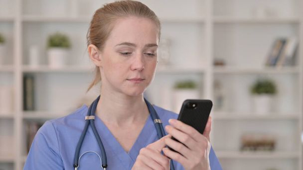 Привлекательная молодая женщина-врач с помощью смартфона
 - Фото, изображение