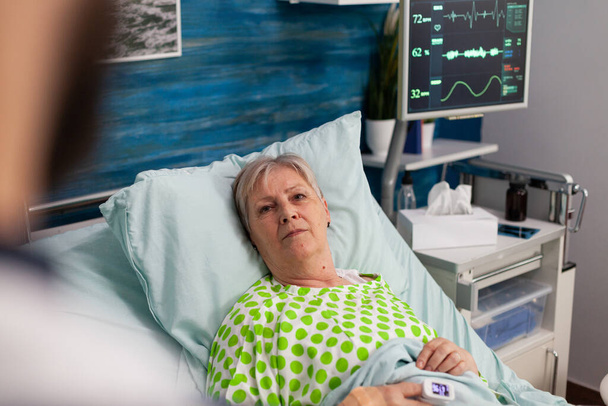 Behinderte Rentnerin liegt im Bett und diskutiert über medizinische Behandlung - Foto, Bild
