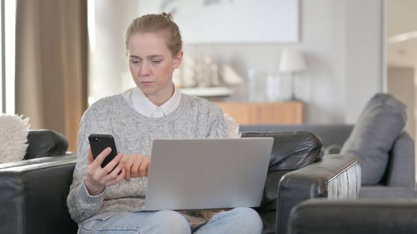 Mulher séria trabalhando no laptop e smartphone em casa
 - Foto, Imagem