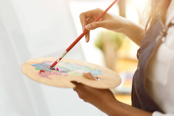 Cropped image of female artist holding and mixing colour on art palette, creative hobby, colourful - Foto, Bild