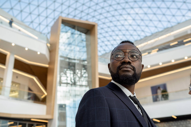 Junger seriöser afrikanischer Geschäftsmann gegen moderne Architektur - Foto, Bild