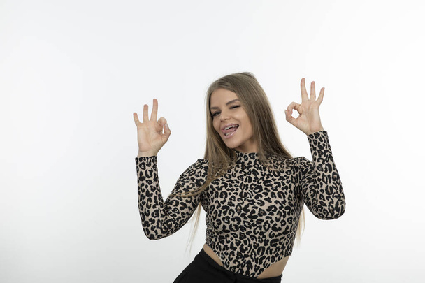 Portrait of beautiful woman in leopard patterned top giving ok sign. High quality photo - Photo, Image