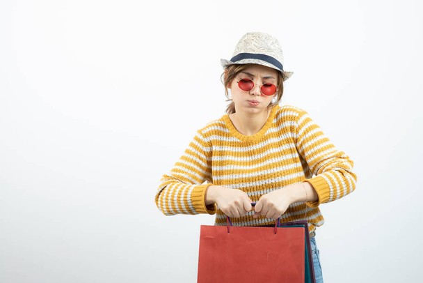 Photo of young brunette woman in sunglasses holding shopping bags. High quality photo - Fotó, kép