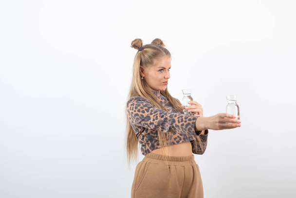 Photo of beautiful woman in crop top with glass of water posing and standing. High quality photo - Photo, Image