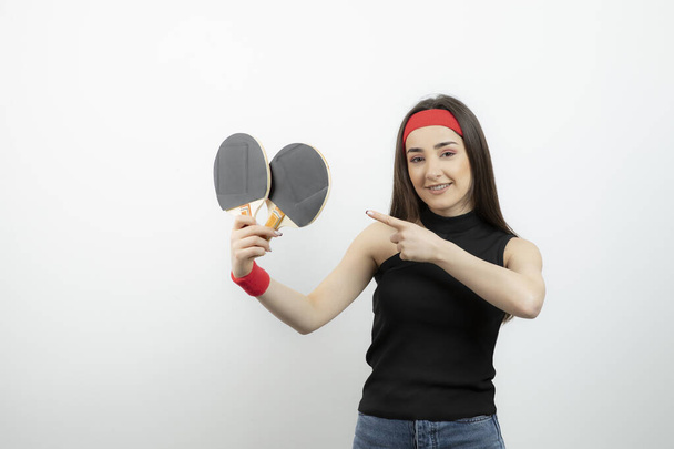 Photo of cute woman player pointing at badminton rackets . High quality photo - Photo, Image