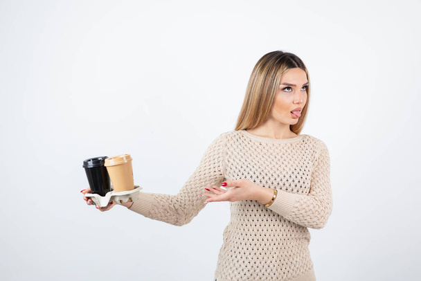Photo of young woman standing and holding two cups of coffee in a carton . High quality photo - Zdjęcie, obraz