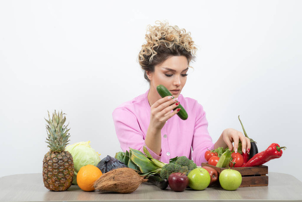 красива жінка позує з різними фруктами та овочами на столі
 - Фото, зображення