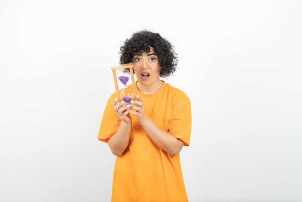 woman in orange t-shirt and posing with hourglass - Photo, Image