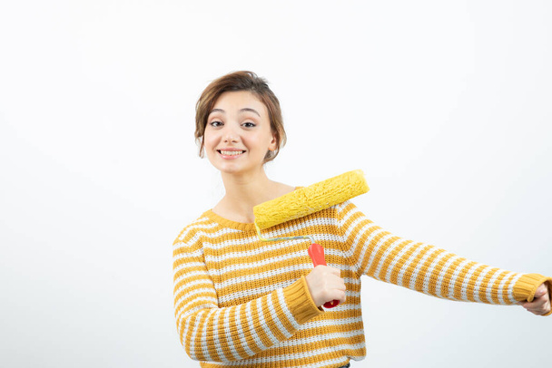 Photo of young woman standing and holding a paint roller in her hand. High quality photo - Photo, Image