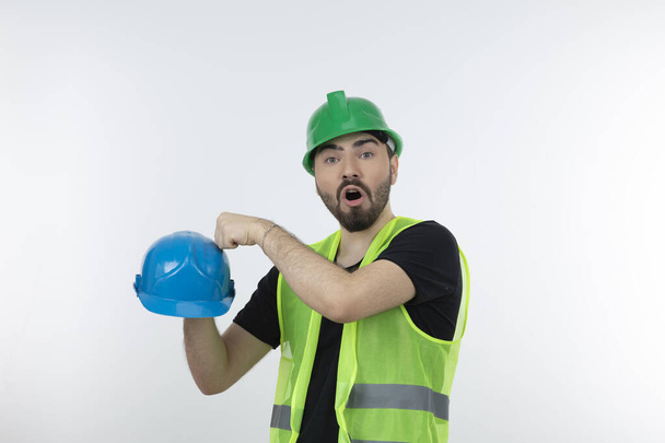 男の工業労働者のショット緑のベストハード帽子をパンチしようとしています。高品質の写真 - 写真・画像