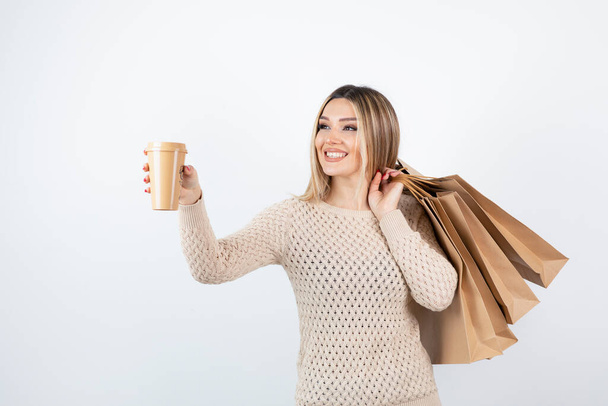 Image of nice-looking woman standing and holding paper bags with cup . High quality photo - Photo, Image
