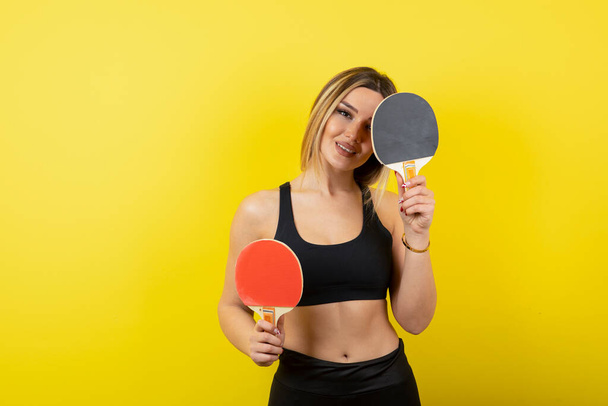 портрет красивой молодой женщины с теннисной ракеткой на желтом фоне - Фото, изображение