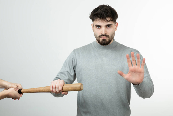 Photo of handsome man standing near baseball bat over white wall . High quality photo - Photo, Image