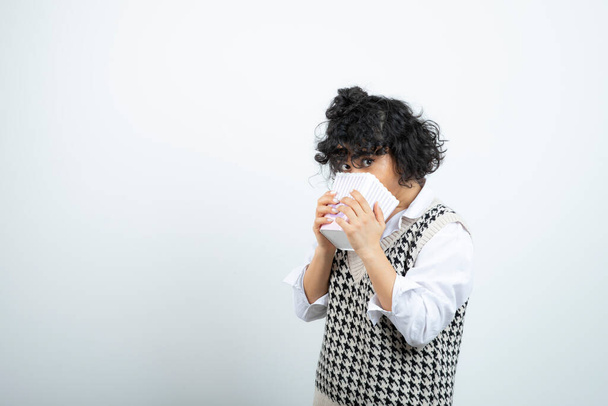 Beautiful curly girl with knitted jacket eating popcorn. High quality photo - 写真・画像