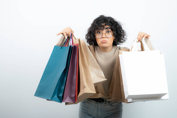 ショッピングバッグの束を保持眼鏡でブルネットの女性の画像。高品質の写真 - 写真・画像