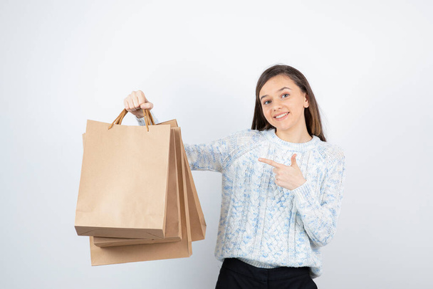 Portré tini lány pulóverben kezében bevásárló táskák - Fotó, kép