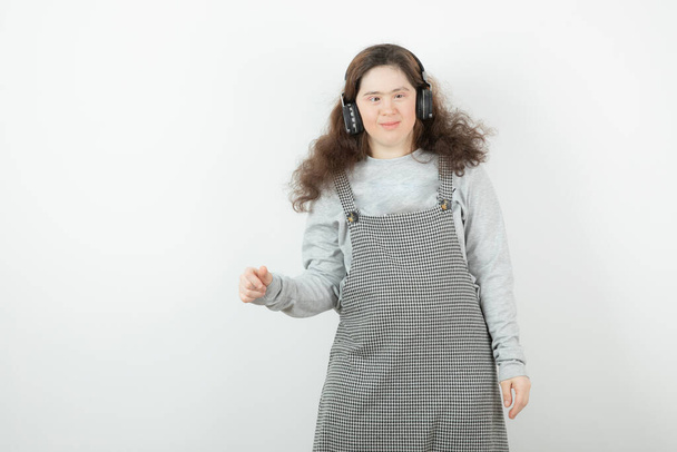 Foto de una chica bonita de pie y escuchando música en los auriculares. Foto de alta calidad - Foto, imagen