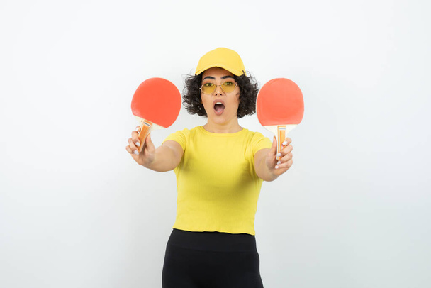 mulher em t-shirt amarela posando no fundo branco com raquetes de ping pong - Foto, Imagem