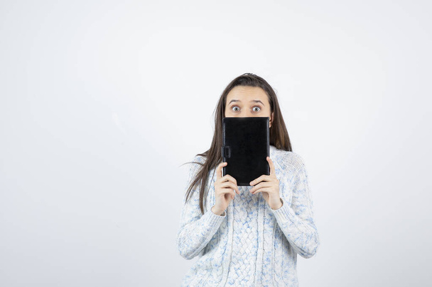 dívka na sobě svetr pózování s notebookem na bílém pozadí - Fotografie, Obrázek