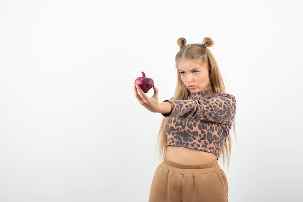 Immagine di giovane donna in crop top con cipolla rossa in mano. Foto di alta qualità - Foto, immagini