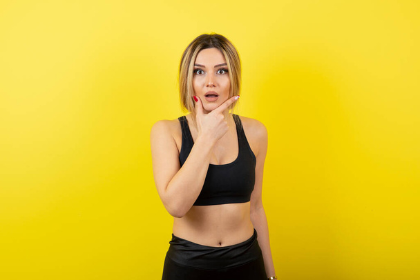 young beautiful woman in a black t-shirt and a yellow sweatshirt on a light background - Photo, Image