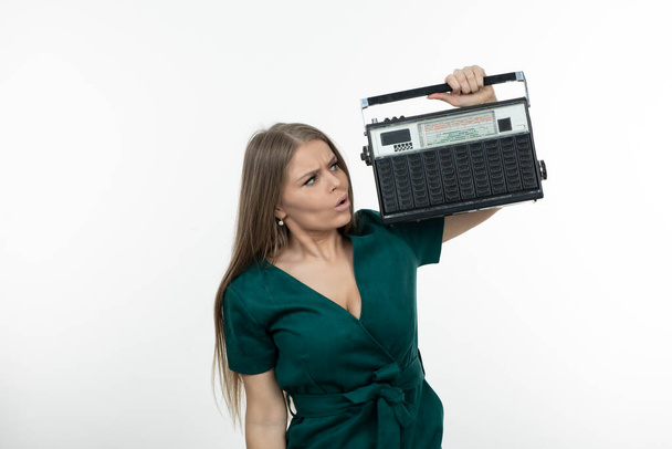 Mujer joven en vestido verde sosteniendo receptor de radio portátil. Foto de alta calidad - Foto, imagen