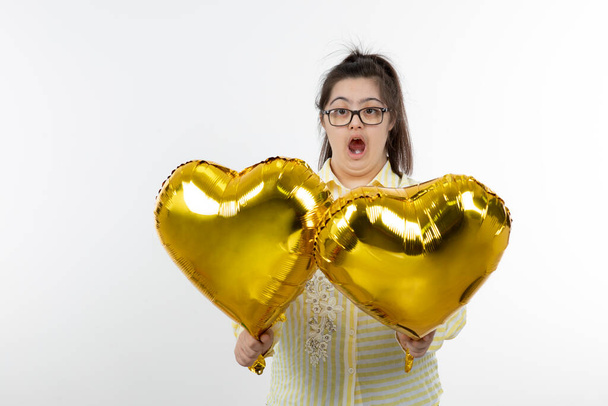ragazza con sindrome di Down in posa con palloncini cuore d'oro - Foto, immagini