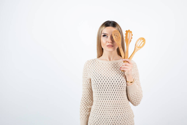 Foto de mujer joven atractiva de pie y sosteniendo herramientas de cocina. Foto de alta calidad - Foto, Imagen
