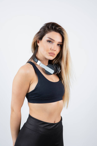 красива молода жінка в спортивному одязі позує з навушниками на шиї
 - Фото, зображення