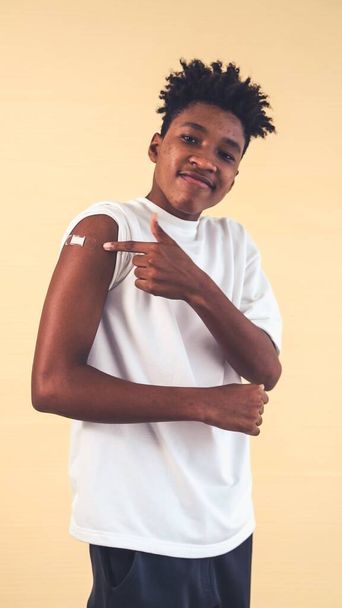 Αφρο-Αμερικανός έφηβος δείχνει COVID-19 εμβόλιο επίδεσμο χαρούμενα - Φωτογραφία, εικόνα