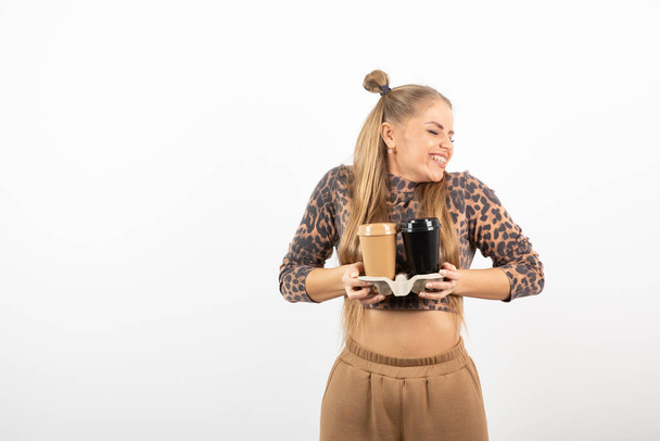 Photo of beautiful young girl in crop top holding cups of latte. High quality photo - Photo, Image