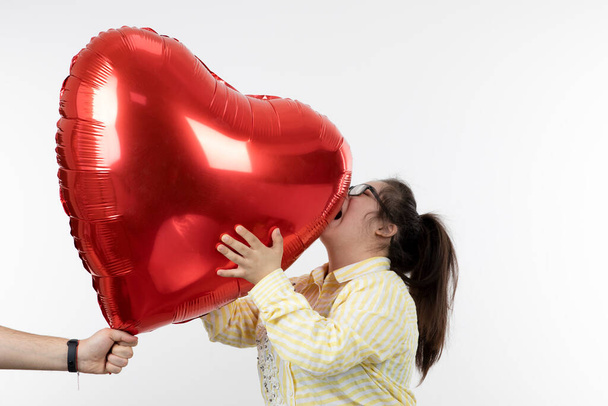 дівчина з синдромом Дауна позує з червоною серцевою кулею
 - Фото, зображення