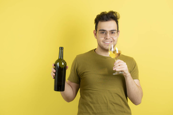 Photo of young model holding glass and bottle of white wine. High quality photo - Photo, image