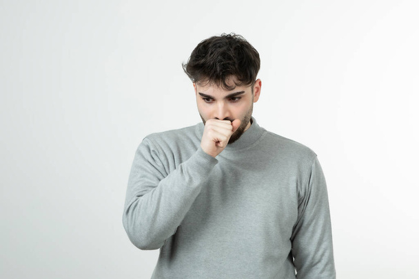 Photo of handsome man in gray sweatshirt coughing over gray. High quality photo - Photo, Image