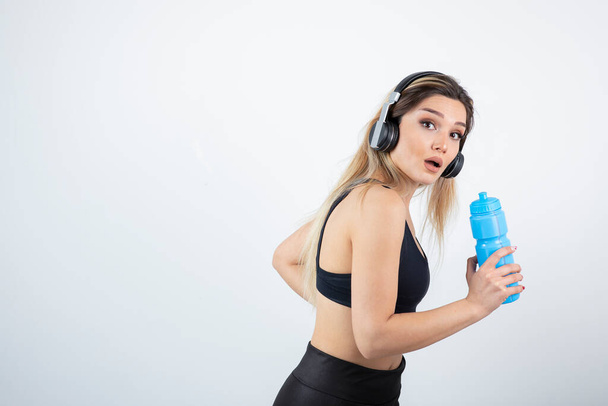  junge sportliche Frau mit Kopfhörer und Flasche - Foto, Bild