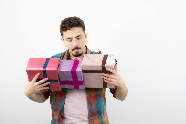 Portrét atraktivního muže držícího nad bílou zdí krabice s dárky. Kvalitní fotografie - Fotografie, Obrázek