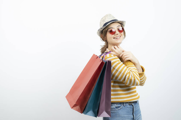 Photo of young brunette woman in sunglasses holding shopping bags. High quality photo - Фото, зображення