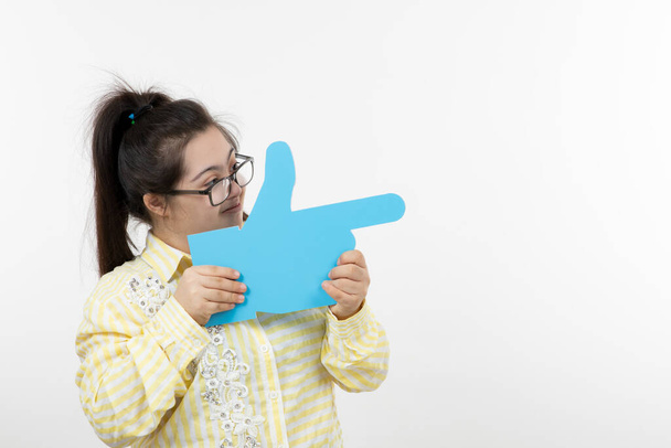 Девушка с синдромом Дауна позирует с голубой бумагой в форме руки - Фото, изображение