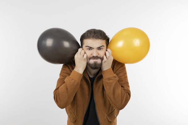 Jeune homme brune barbe tenant des ballons jaunes et noirs. Photo de haute qualité - Photo, image