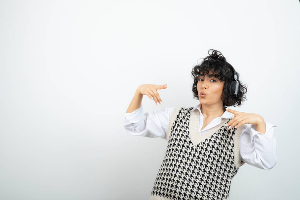 Morena encaracolado mulher em fones de ouvido ouvindo música e dança. Foto de alta qualidade - Foto, Imagem