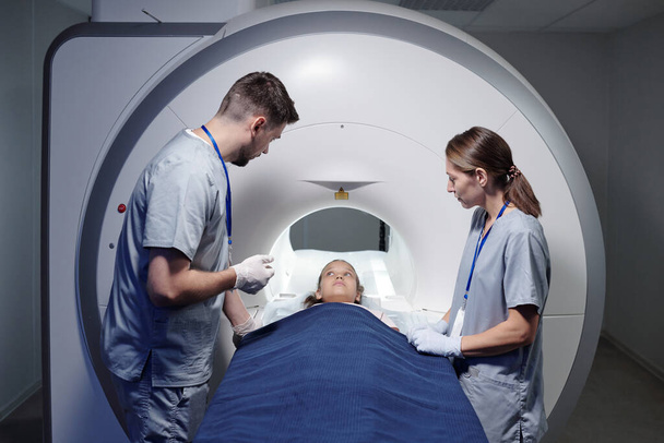 Radiolodzy konsultując się z małą dziewczynką przed badaniem rezonansu magnetycznego - Zdjęcie, obraz
