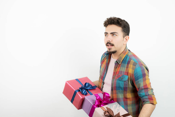 Portrait d'un homme séduisant tenant des boîtes cadeaux au-dessus d'un mur blanc. Photo de haute qualité - Photo, image